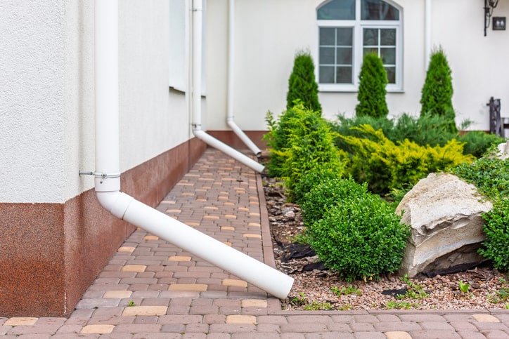 White PVC downspout extensions directing water from gutters in Salt Lake City, Utah